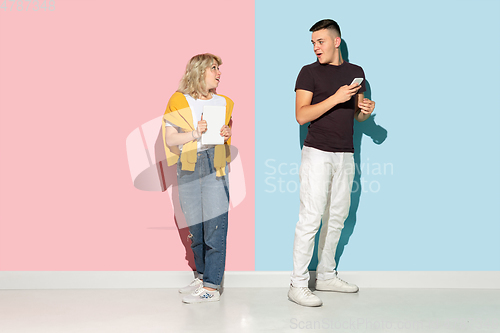 Image of Young emotional man and woman on pink and blue background