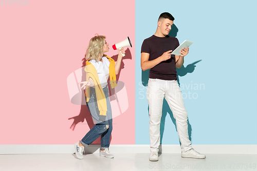 Image of Young emotional man and woman on pink and blue background