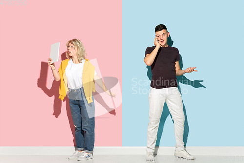 Image of Young emotional man and woman on pink and blue background