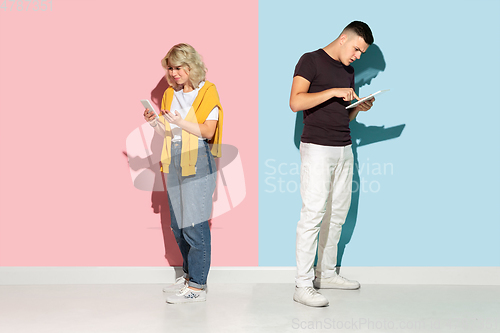 Image of Young emotional man and woman on pink and blue background