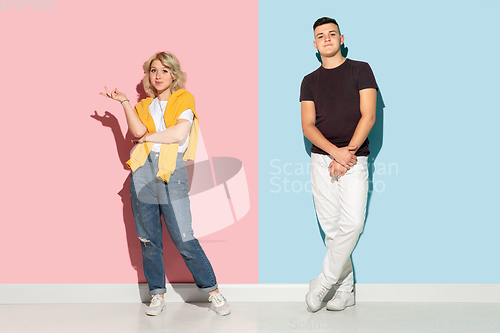 Image of Young emotional man and woman on pink and blue background