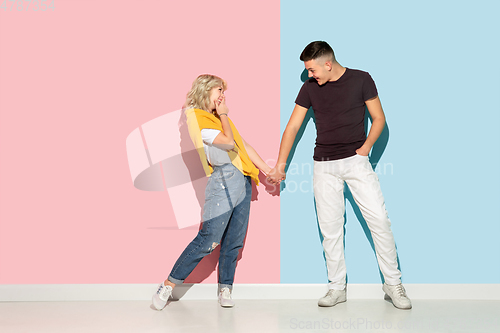 Image of Young emotional man and woman on pink and blue background