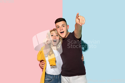 Image of Young emotional man and woman on pink and blue background