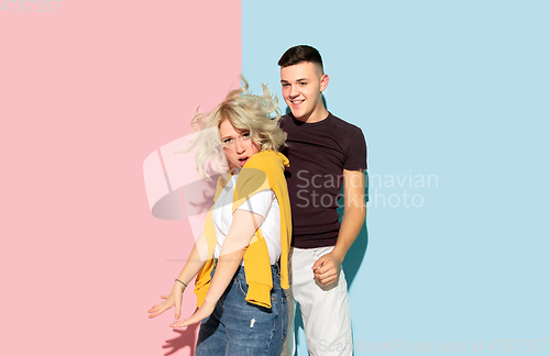 Image of Young emotional man and woman on pink and blue background