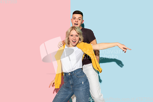 Image of Young emotional man and woman on pink and blue background