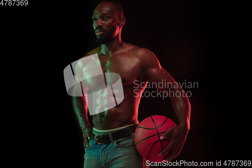 Image of Young african-american basketball player against dark background