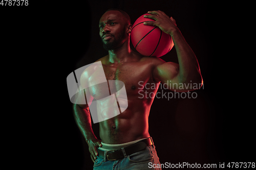 Image of Young african-american basketball player against dark background