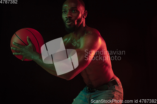 Image of Young african-american basketball player against dark background