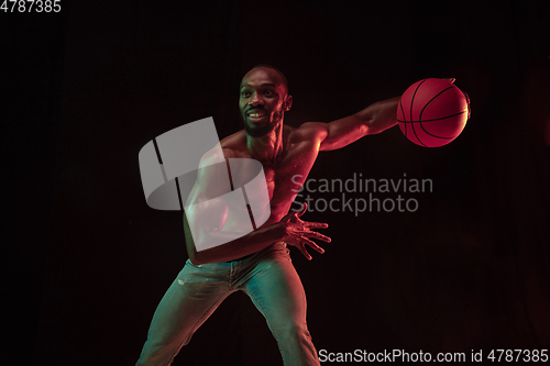 Image of Young african-american basketball player against dark background