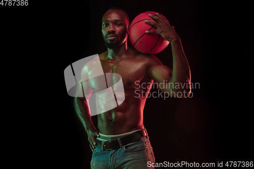 Image of Young african-american basketball player against dark background