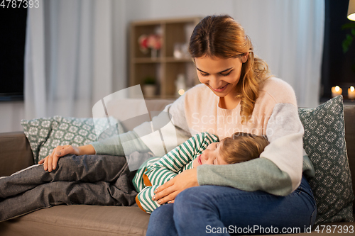 Image of happy mother with sleeping little son at home