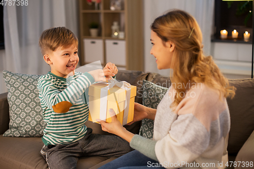 Image of mother giving present to her little son at home