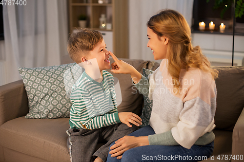 Image of happy mother touching little son's nose at home