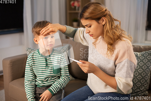 Image of sad mother with thermometer and ill son at home