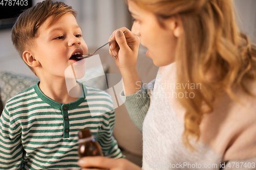 Image of mother giving medication or cough syrup to ill son