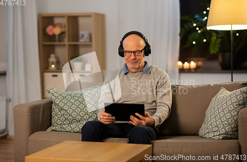 Image of senior man with tablet pc and headphones at home