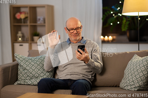 Image of old man with smartphone having video call at home