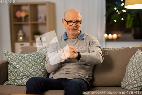 Image of senior man looking at wristwatch at home