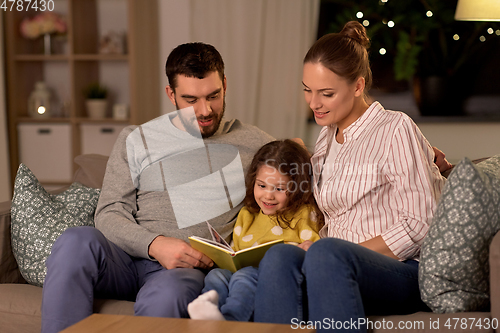 Image of happy family reading book at home at night