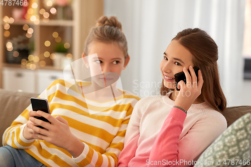 Image of happy teenage girls with smartphones at home