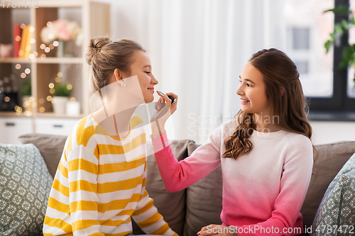 Image of happy teenage girls doing make up at home