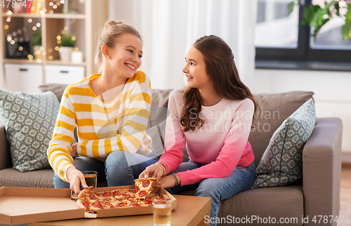 Image of happy teenage girls eating takeaway pizza at home