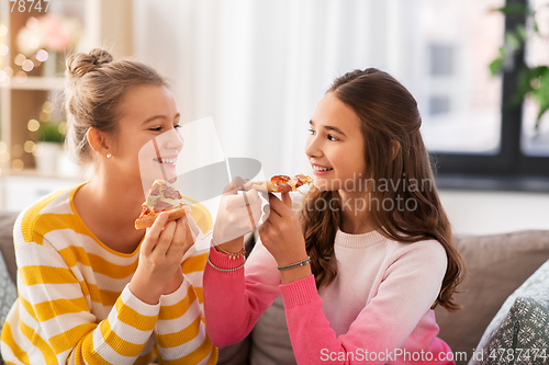 Image of happy teenage girls eating pizza at home