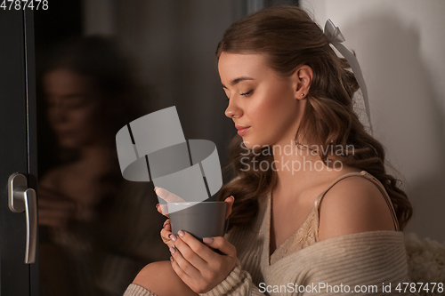 Image of woman with coffee or tea cup at window at home