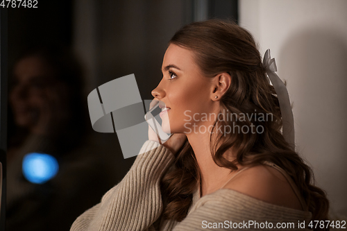 Image of woman calling on smartphone at window at night