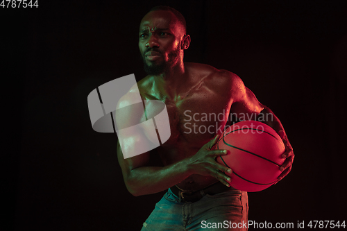 Image of Young african-american basketball player against dark background