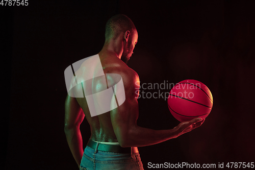 Image of Young african-american basketball player against dark background