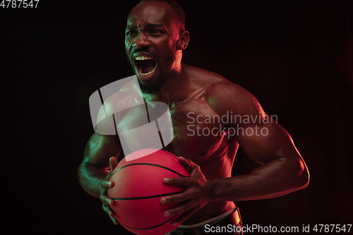 Image of Young african-american basketball player against dark background