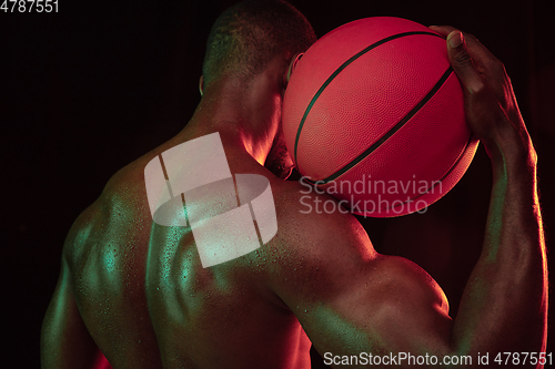 Image of Young african-american basketball player against dark background