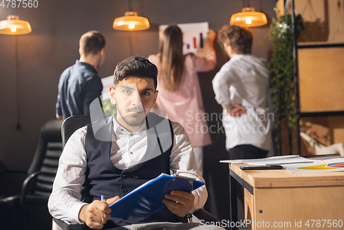 Image of Colleagues working together in modern office using devices and gadgets during creative meeting