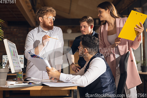 Image of Colleagues working together in modern office using devices and gadgets during creative meeting