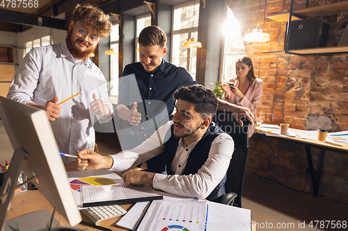 Image of Colleagues working together in modern office using devices and gadgets during creative meeting