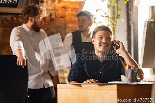 Image of Colleagues working together in modern office using devices and gadgets during creative meeting