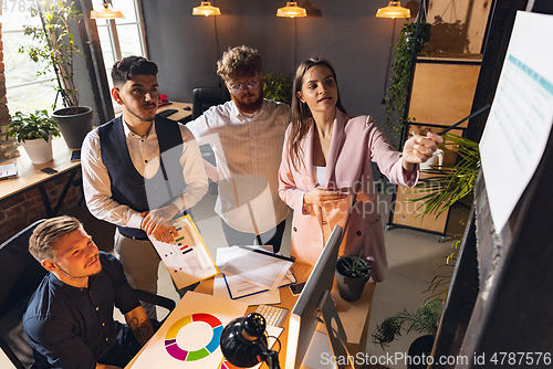 Image of Colleagues working together in modern office using devices and gadgets during creative meeting