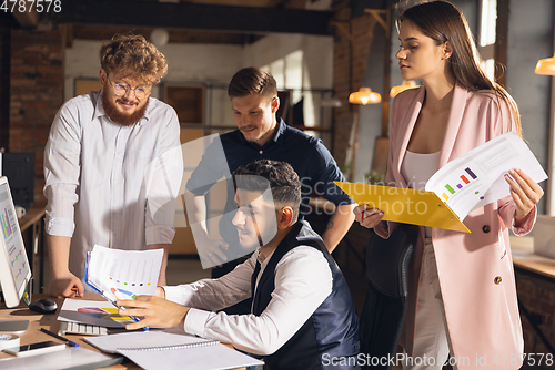 Image of Colleagues working together in modern office using devices and gadgets during creative meeting