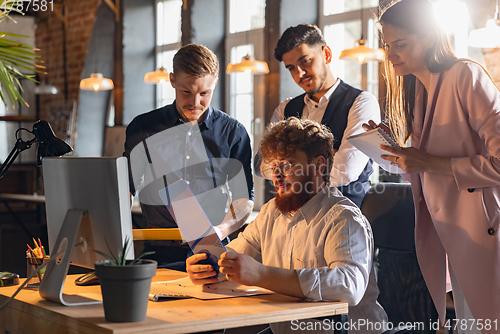 Image of Colleagues working together in modern office using devices and gadgets during creative meeting