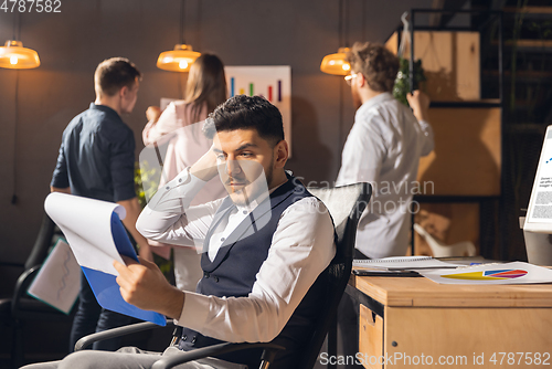 Image of Colleagues working together in modern office using devices and gadgets during creative meeting