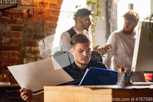 Image of Colleagues working together in modern office using devices and gadgets during creative meeting