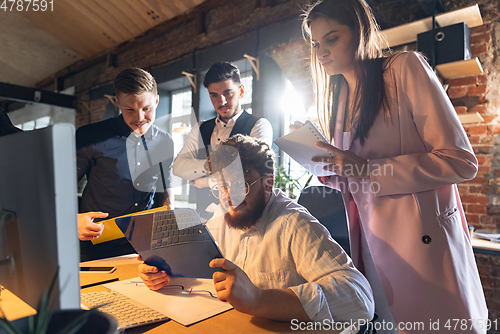 Image of Colleagues working together in modern office using devices and gadgets during creative meeting