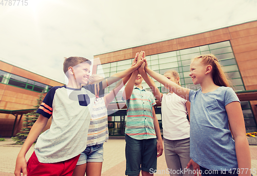 Image of group of children making high five at school yard