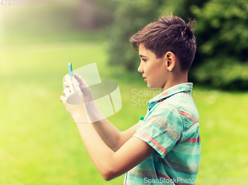 Image of boy with smartphone playing game in summer park