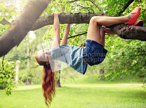 Image of happy little girl hanging on tree in summer park