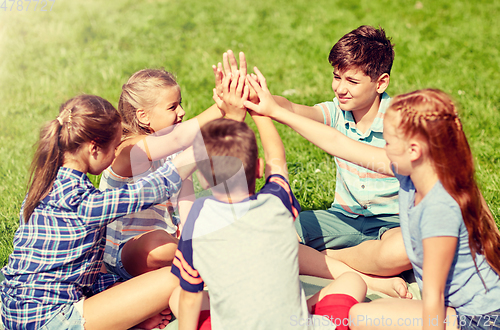 Image of group of happy kids making high five outdoors