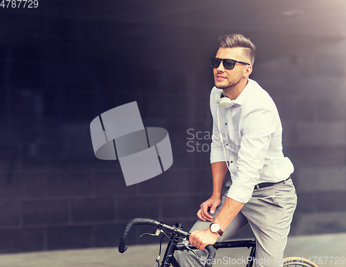 Image of man with bicycle and headphones on city street