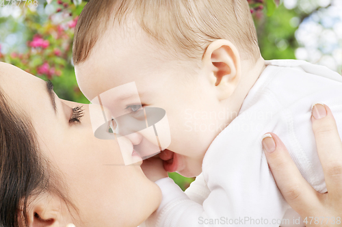 Image of close up of mother kissing baby over garden