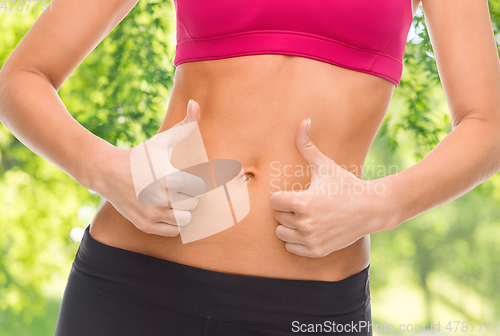 Image of close up of woman showing tummy and thumbs up